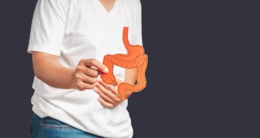 Gri arka planda dururken kolon sembolünü tutan ellerin yakın çekimi. Tıbbi ve sağlık hizmeti kavramı