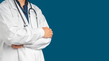 Mavi arka planda kolları çapraz duran üniformalı bir doktorun göbeğinde. Kaliteli tıbbi hizmetler. Mesaj için yer var. Tıbbi personel, tıp ve bilim konsepti