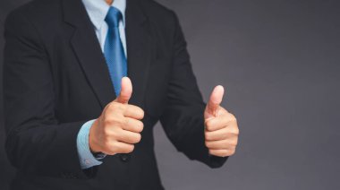 Takım elbiseli bir işadamı, gri arka planda dururken iki elini de kaldırıyor. Müşteri hizmetleri ve memnuniyet araştırmaları konsepti. Yakın plan fotoğraf.