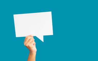 Stüdyonun mavi arka planına karşı beyaz bir konuşma balonu tutan yakın plan. Yakın plan fotoğraf. Metin için boşluk