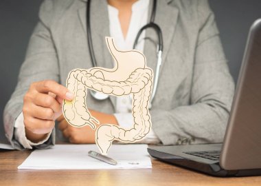 Hastanedeki masada otururken kolon sembolü tutan doktorun eli. Kabızlık ve ishalin tedavisi ve önlenmesi. Bağırsak mikroflorası ve probiyotik. Sağlık hizmetleri kavramı