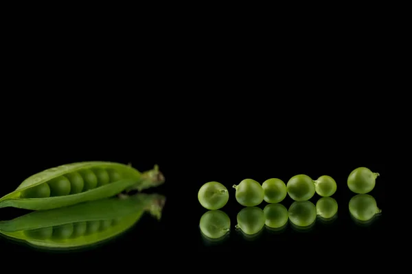Pea pods on a black background, green peas in a pod on a dark background