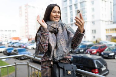 Genç bir kadın sokaktaki bir telefonla video ile iletişim kuruyor..
