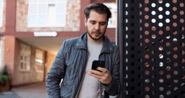 Sakin, çekici, beyaz, orta yaşlı, elinde cep telefonu olan bir adam..