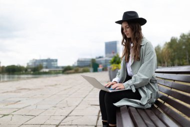 Genç ve güçlü kadın yazılım geliştirici dışarıda dizüstü bilgisayarda çalışıyor..