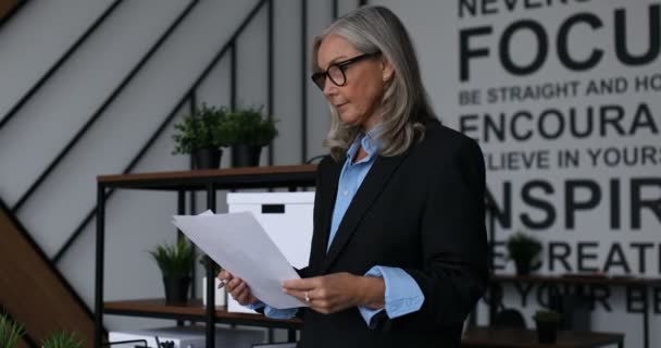 近代的なオフィスの背景に彼女の手の文書を持つビジネスマン — ストック動画