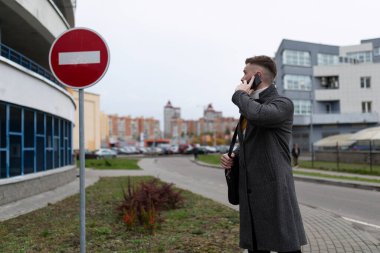 Otoparkın yanında telefonla konuşan bir adam..