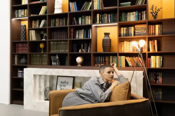 stylish woman resting in a chair on the background of the interior with a home library.