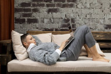 Yorgun, beyaz bir kadın kanepede yatarken dizileri izlerken dinleniyor..