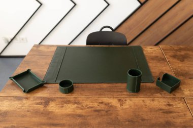 Ofis içi, üzerinde kırtasiye malzemesi depolamak için deri ped ve aksesuarlar olan bir çalışma masası ile dolu..