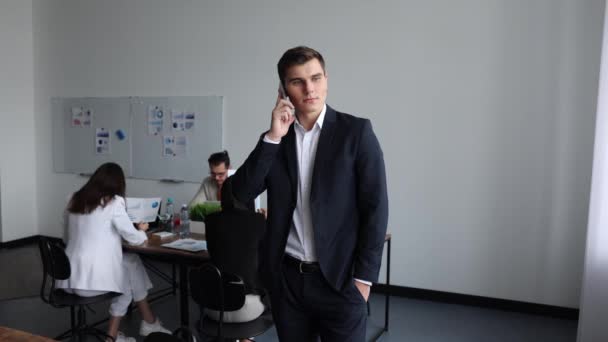 Manajer Proyek Berbicara Telepon Genggam Dengan Latar Belakang Kantor Oleh — Stok Video
