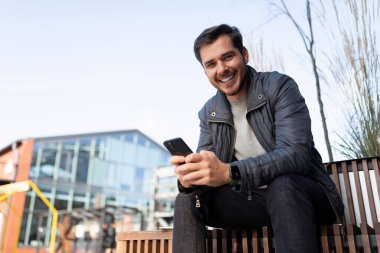 Dışarıda telefonu olan ceketli genç bir adam..