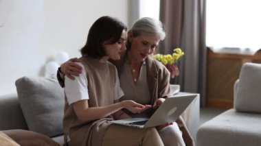 Yetişkin kız, yaşlı anneye dizüstü bilgisayarın ve modern aletlerin nasıl kullanılacağını anlatıyor..