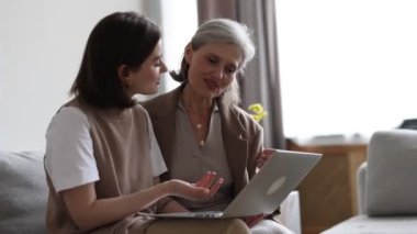 Yetişkin bir kız, annesine bilgisayar ekranını gösteren modern aletleri ve elektronik aletleri nasıl kullanacağını açıklar..