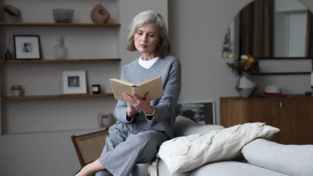 Stylish Gray Haired Woman Home Reading Book Sitting Back Sofa — Stock Video