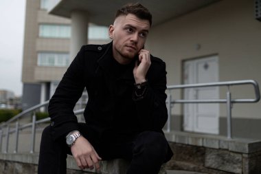 Şehrin arka planında siyah ceketli şık ve vahşi bir adam var..