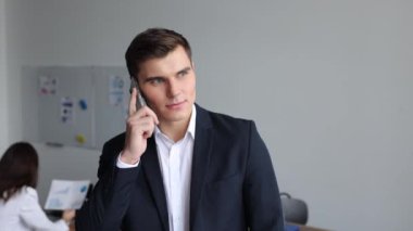 Genç, hırslı bir lider telefonda iş arkadaşlarının arka planına karşı konuşuyor..