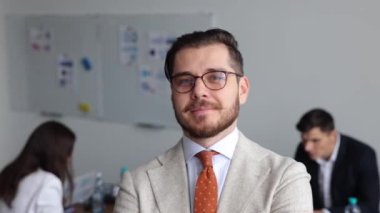 Gözlüklü bir girişimin başarılı girişimci yaratıcısı ve çalışan bir meslektaşın arka planında bir iş elbisesi.