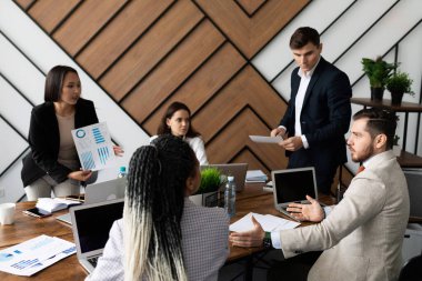 İş adamları büyük bir masaüstünde dizüstü bilgisayarlarla iş toplantısı yapıyorlar..