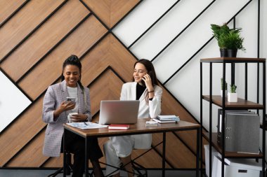 Bayan meslektaşlar ofiste çalışıyor ve telefonda konuşuyorlar..