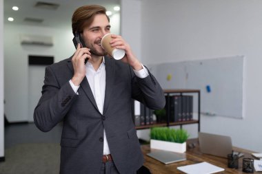 Kahve molası sırasında erkek simsarın portresi ofiste telefonda konuşuyor..