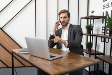 Ofiste bir müvekkille telefonda konuşmakla ve dizüstü bilgisayara bakmakla meşgul..