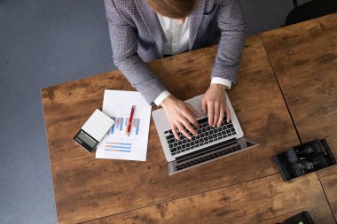 Ofis çalışanı, haritalar ve dizüstü bilgisayarla finans sektöründe çalışıyor..