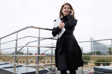 Kampüs binasının merdivenlerinde internet bağlantısı kullanarak konuşan kendine güvenen bir iş kadını..