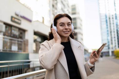 Şık şehir kızı şehirde dolaşıyor ve müzik dinliyor..