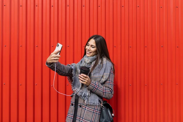 young woman designer making selfie photo on red background.