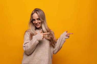 İzole edilmiş arka planda ellerini duvara doğru gösteren genç bir kadın..