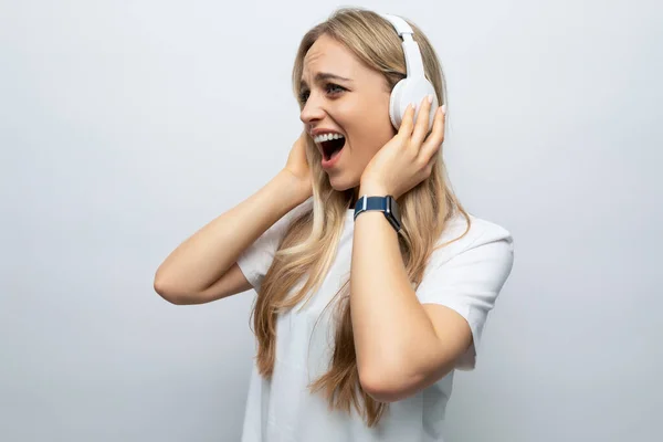 young woman listening to loud music with headphones among white background.