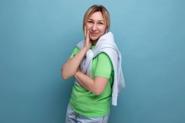 Sarışın, gülümseyen mütevazı bir genç kadının portresi. Stüdyonun mavi arka planında fotokopi alanı olan sıradan bir kıyafet içinde..