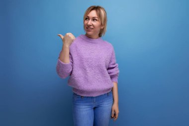 Mor kazaklı hoş, sevimli sarışın bayan danışman elini mavi bir arka planda fotokopi aletiyle gösteriyor..