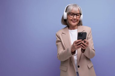 60 'lı yılların şık ceketli büyükannesi büyük kulaklıklarla müzik dinliyor..