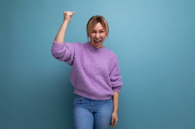 Şanslı kazanan, enerjik, hoş, sarışın, parlak bir arka planda yüksek sesle gülen genç bir kadın..