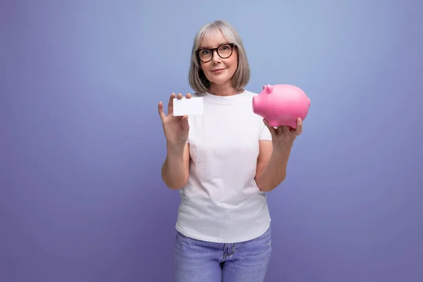 social insurance. mature woman with gray hair keeps her savings on a bank account on a studio background with copy space.