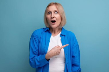 Mavi arka planda, görsel ortamda şok olmuş olgun bir kadın..