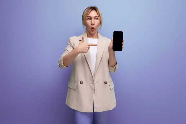 close-up surprised business woman in store showing smartphone mockup in studio with copy space.