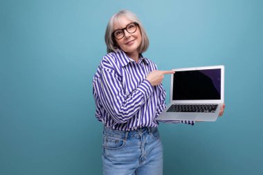 Orta yaşlı kadın, parlak stüdyo geçmişine sahip dizüstü bilgisayarda ustalaşıyor..