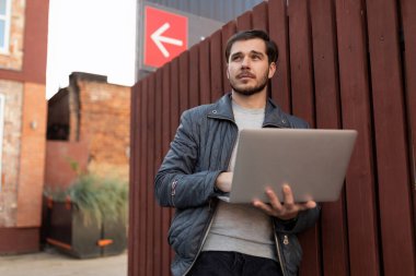 Bilgisayarlı başarılı beyaz adam açık havada çalışıyor..