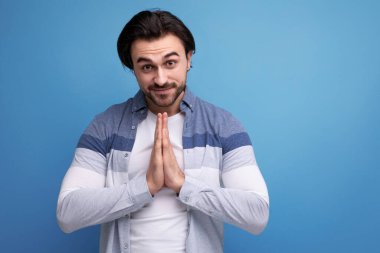 Stüdyonun arka planında, umutlu, genç, vahşi esmer adam..