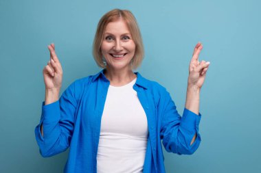 Fotokopi alanı olan mavi bir arka planda çekici görünümlü 50 'li yaşlardaki enerjik kadın..