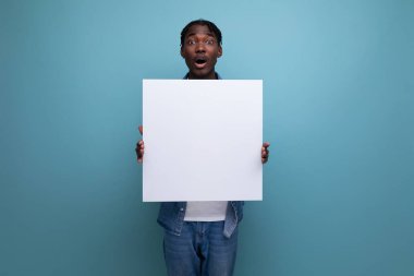 Kot ceketli Afrikalı bir adam elinde bir gazete posteri tutuyor..