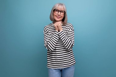 60 'lı yaşlarda hoş bir kadının parlak bir stüdyo arka planında şık bir portresi..