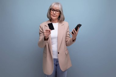 60 'ların şık görünümlü orta yaşlı iş kadını, kredi kartıyla fotokopi çekilen parlak bir stüdyo arka planında ödeme yapıyor..