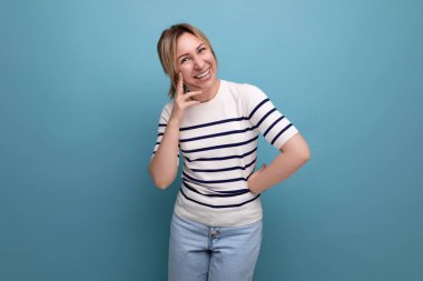 Mavi arka planda çizgili süveterli, pozitif, neşeli, sarışın bir kızın fotokopi alanı olan yakın plan fotoğrafı..