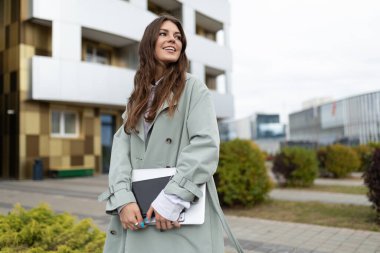 Binanın arka planında belgeleri olan Avrupalı genç iş kadını.