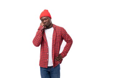 Kırmızı ekose gömlekli ve kot pantolonlu genç etnik Afrikalı adam izole edilmiş beyaz arka planı düşünüyor..