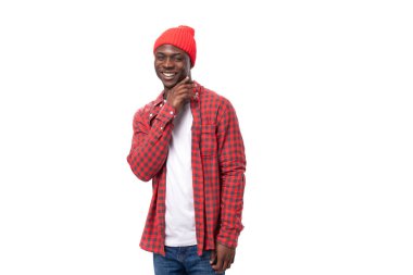 Yakışıklı, utangaç, koyu tenli bir adam. Sıradan bir ekose gömlek giymiş. Beyaz bir arka planda, fotokopi alanı olan..